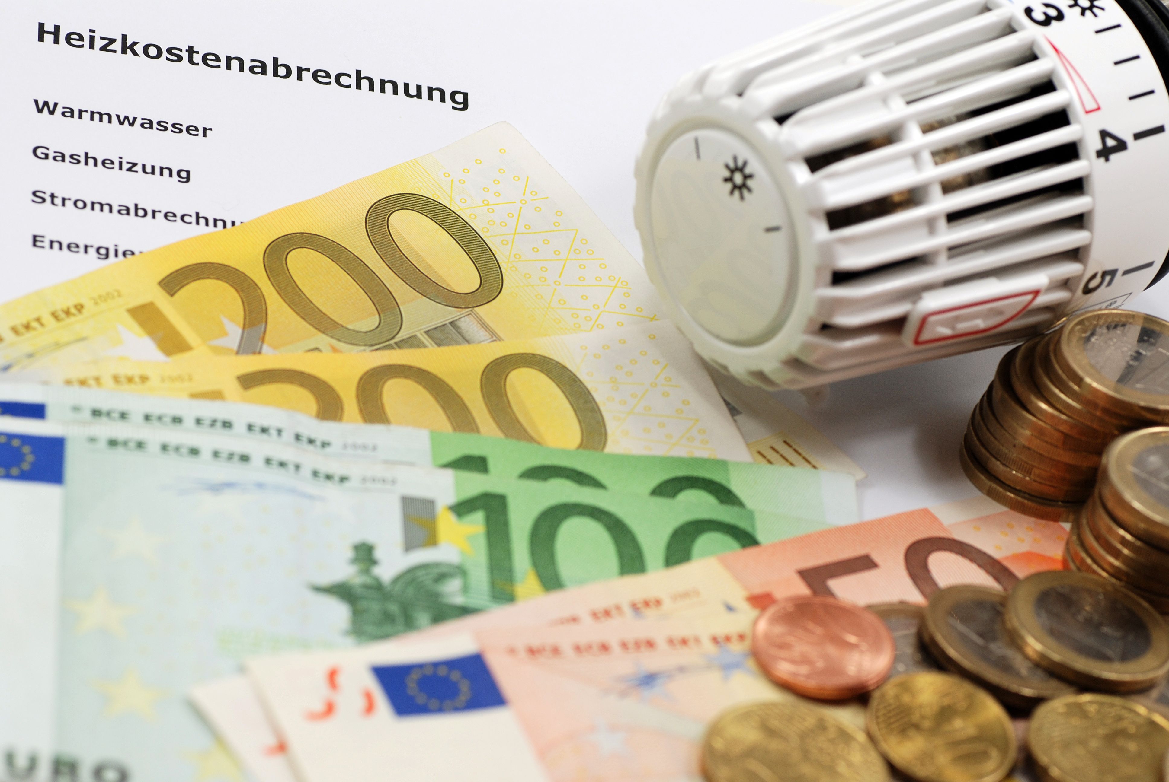 Heizkostenabrechnung mit Geldscheinen, Münzen und Heizungsthermostat